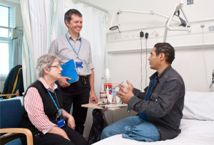 A nurse and doctor talking to a homeless patient sitting on a hospital bed