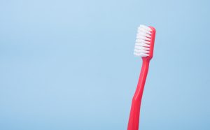 A red toothbrush on a sky blue background