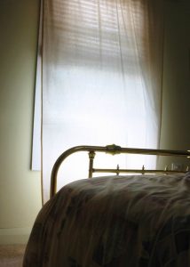 An image of a shadowy bed, with half light from a window