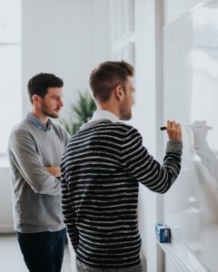 two men writing on a whiteboard